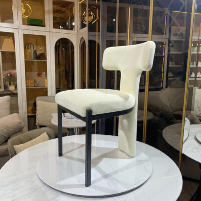 Minimalist black metal frame dining chair with cream bouclé seat.