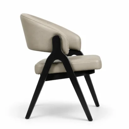 Beige upholstered dining chair with sculptural black wooden frame, back side view