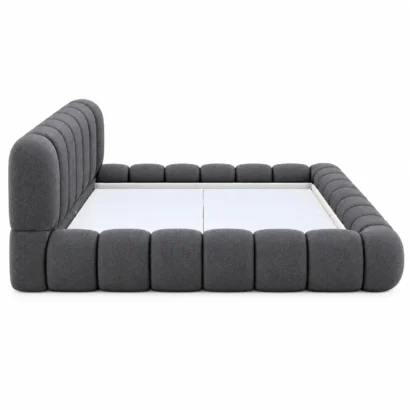 Angled view of a modern charcoal upholstered bed frame with rounded padded sections.